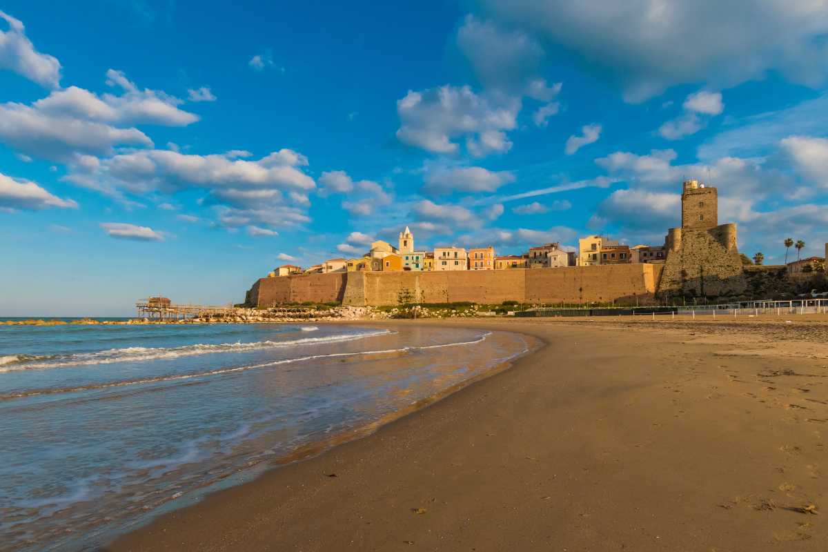 Vista panoramica di Termoli con bambini in spiaggia e il Castello Svevo sullo sfondo